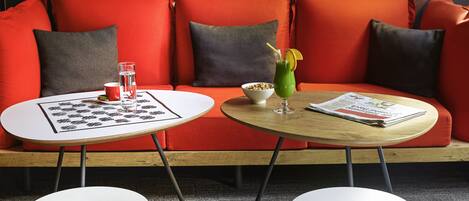A modern living area with a red sofa, two white tables, and a magazine.