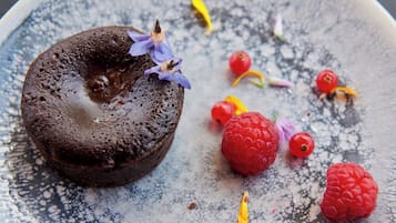 Een dessert op een bord met frambozen en bloemblaadjes.