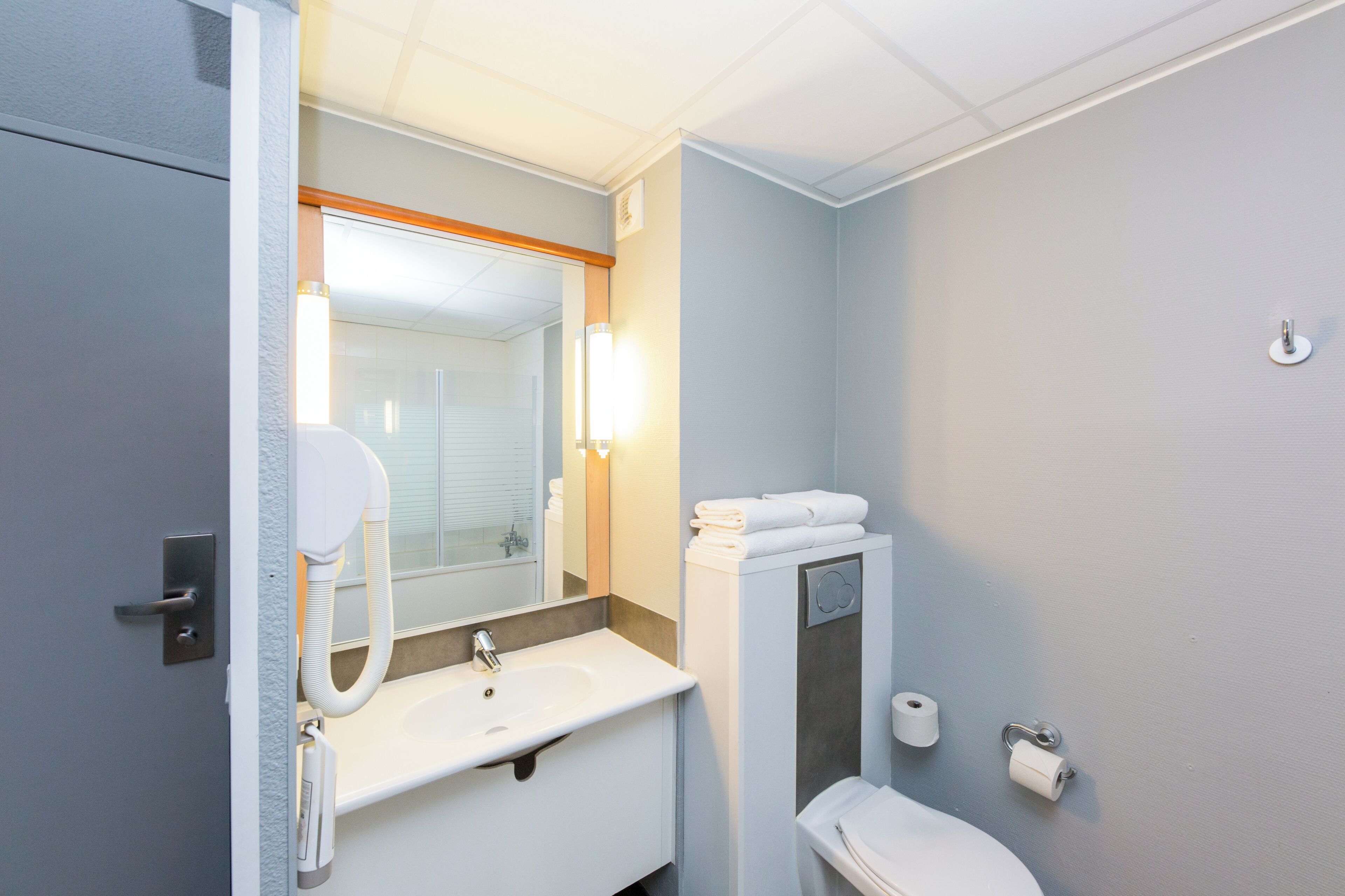 A bathroom with a white sink, a mirror, a toilet, and a towel rack.