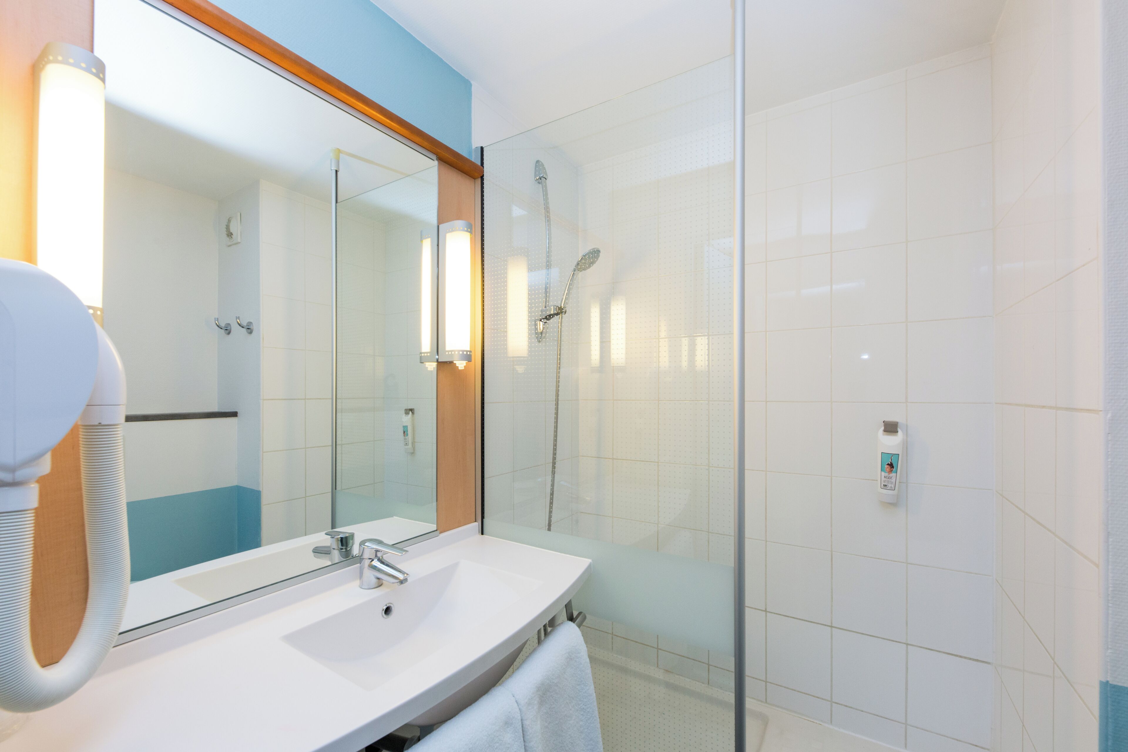 Une salle de bain moderne avec une douche à parois de verre, un lavabo blanc et un grand miroir.