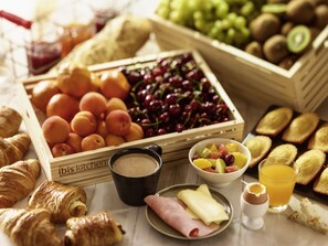 Una bandeja de desayuno con frutas, bollería y bebidas.