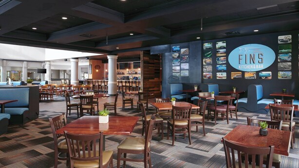 Un restaurant proposant différents types de sièges, notamment des tables et des banquettes, et dont un mur est décoré d’images de voitures.