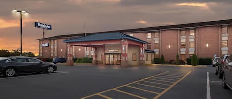 Un hôtel Travelodge avec une façade en briques, une entrée couverte et un parking.