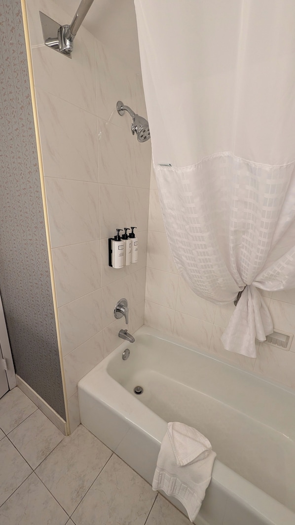 Une salle de bain avec une baignoire, une douche et des toilettes. Des articles de toilette sont accrochés au mur.