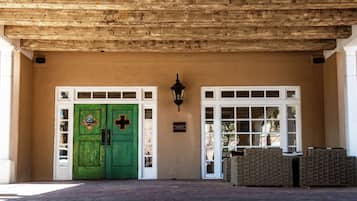 A building entrance with a green door, a white door, and a wall-mounted light fixture.
