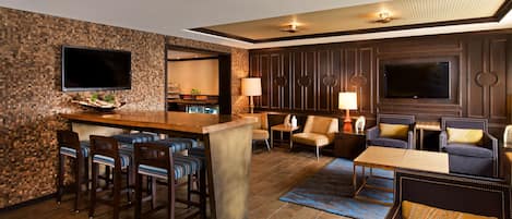 Eine moderne Hotelhalle mit Barbereich, Sitzgelegenheiten und einem Fernseher.