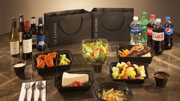 A table with various food items, drinks, and a set of black shopping bags.