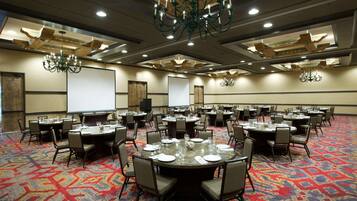 A conference room with multiple round tables, each set with chairs, plates, and glasses.