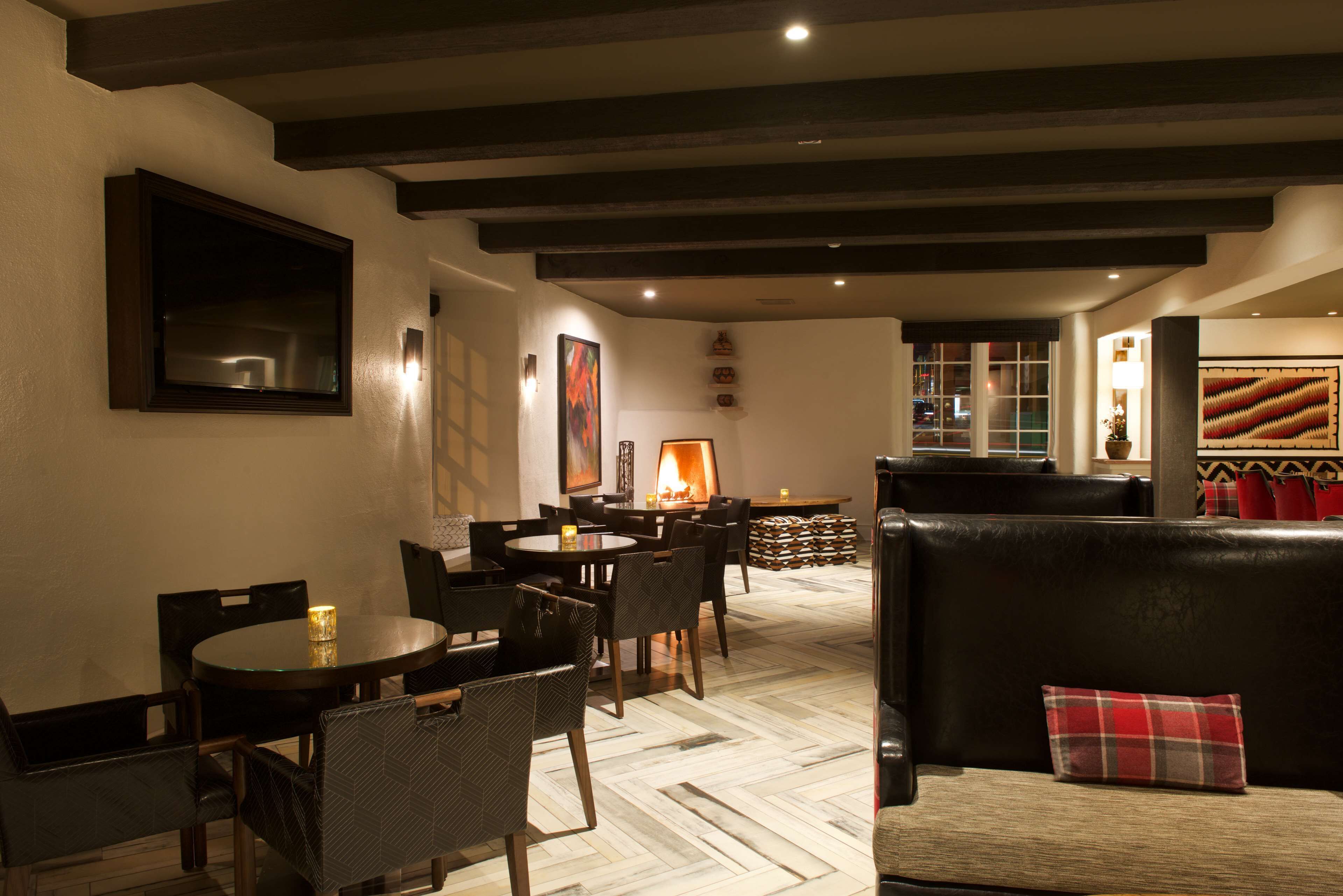 Un interior acogedor con chimenea, asientos de cuero y un comedor con mesas y sillas redondas.