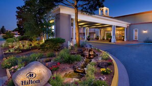 A hotel entrance with a landscaped garden, a stone sign, and a bell tower. - Hilton Santa Fe Historic Plaza (Santa Fe)