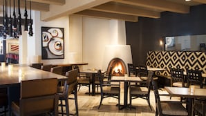 A cozy restaurant with a fireplace, wooden tables, and comfortable seating. - Hilton Santa Fe Historic Plaza (Santa Fe)