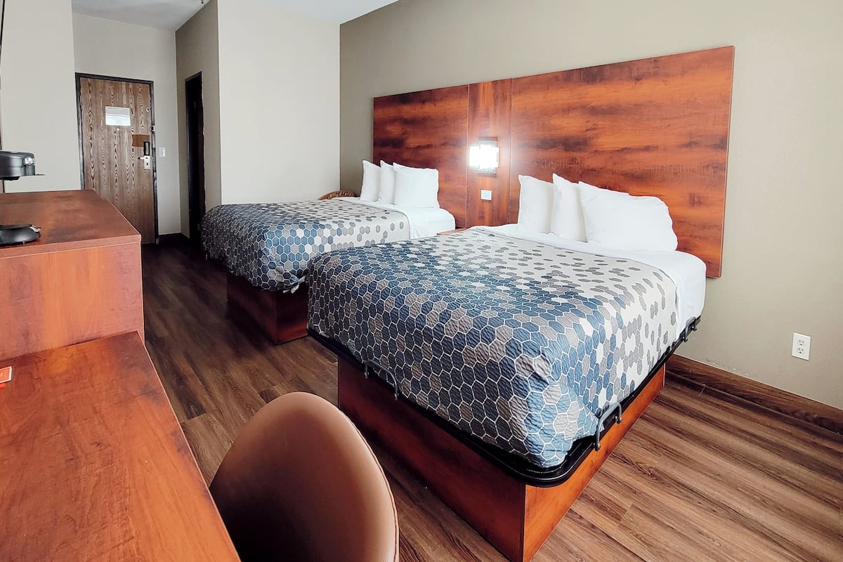 Habitación de hotel con dos camas, un escritorio y una silla.