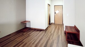 A hallway with wooden flooring, a small table, and a door. - Econo Lodge Fargo - West Acres (Fargo)