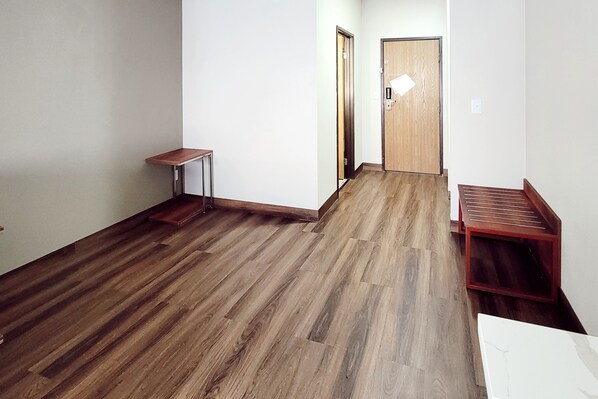 A hallway with wooden flooring, a small table, and a door.