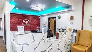 A reception desk with a marble design, a red accent wall, and a clock on the wall. - Econo Lodge Fargo - West Acres (Fargo)