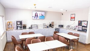 A modern kitchen with white cabinets, a flat-screen TV, a coffee machine, and a microwave. - Econo Lodge Fargo - West Acres (Fargo)