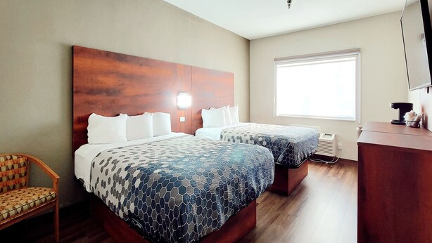 A hotel room with two beds, a wooden headboard, a chair, a desk, and a large window. - Econo Lodge Fargo - West Acres (Fargo)