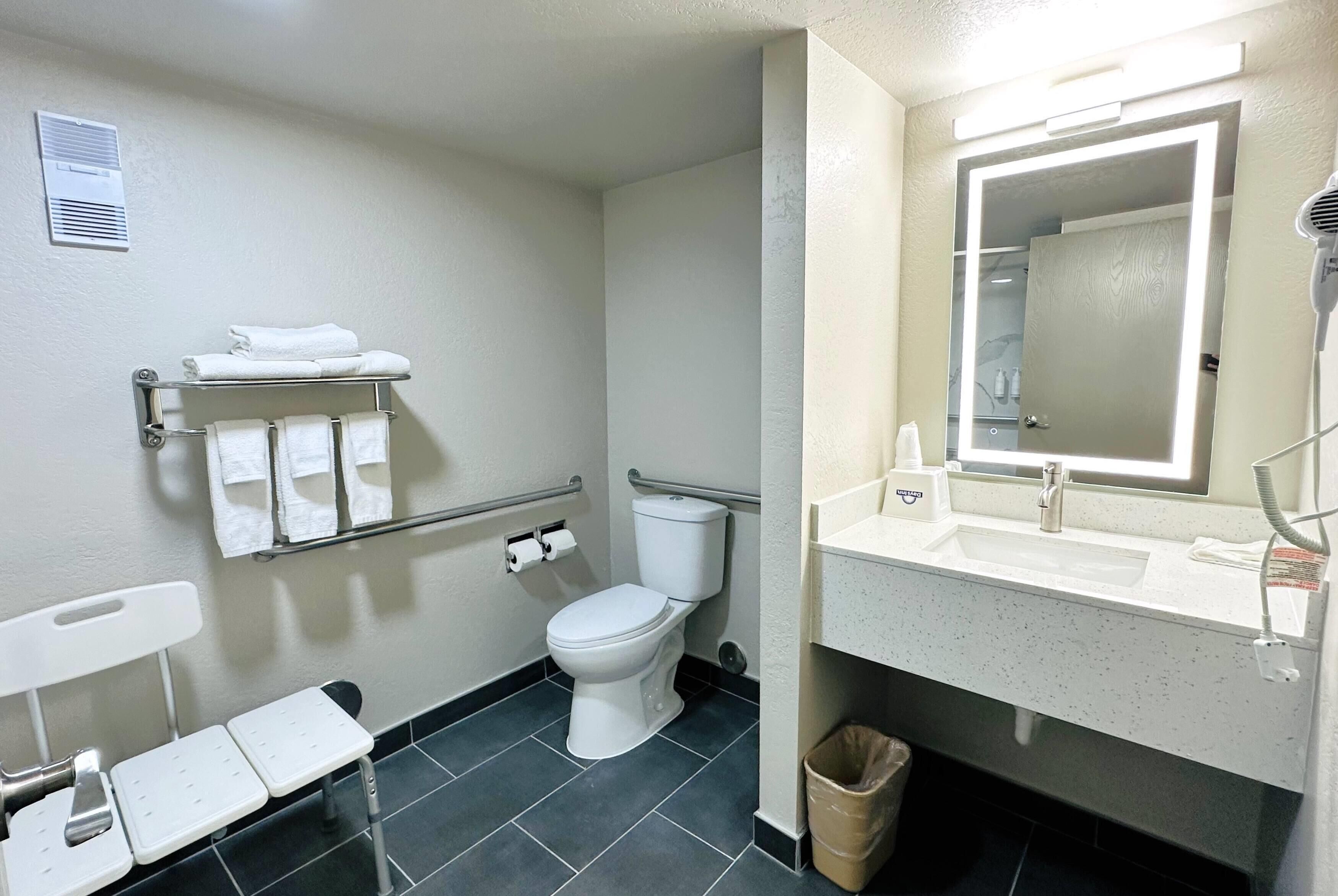 A modern bathroom with a white toilet, a sink with a mirror, and a towel rack with folded towels.