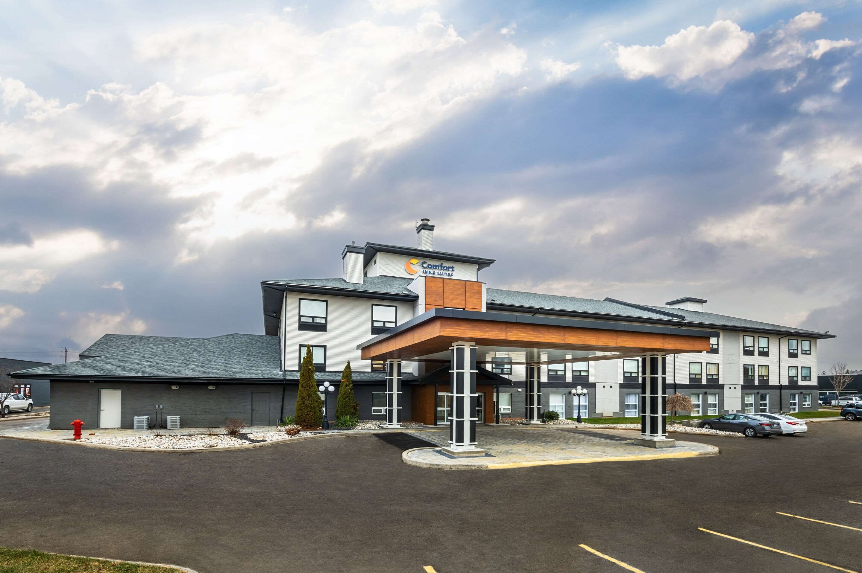 A Comfort Inn & Suites hotel with a covered outdoor area, parking lot, and a clear sky.