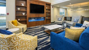 A modern living room with a flat-screen TV, comfortable seating, a fish tank, and a view of the outdoors.
