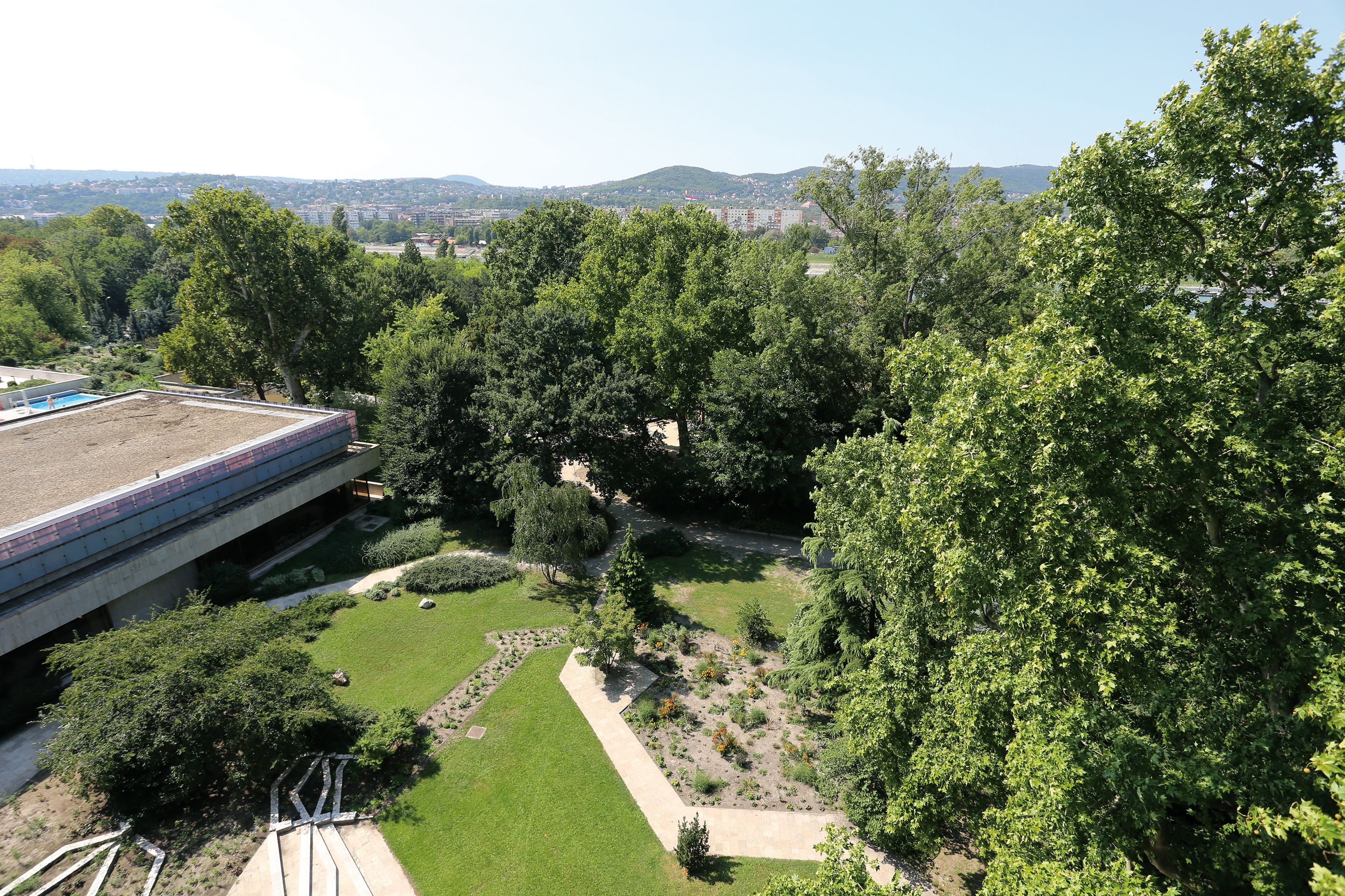 A rooftop garden with a view of a cityscape and mountains in the distance.