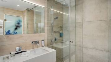 A modern bathroom with a glass-enclosed shower, a white sink, and a large mirror.