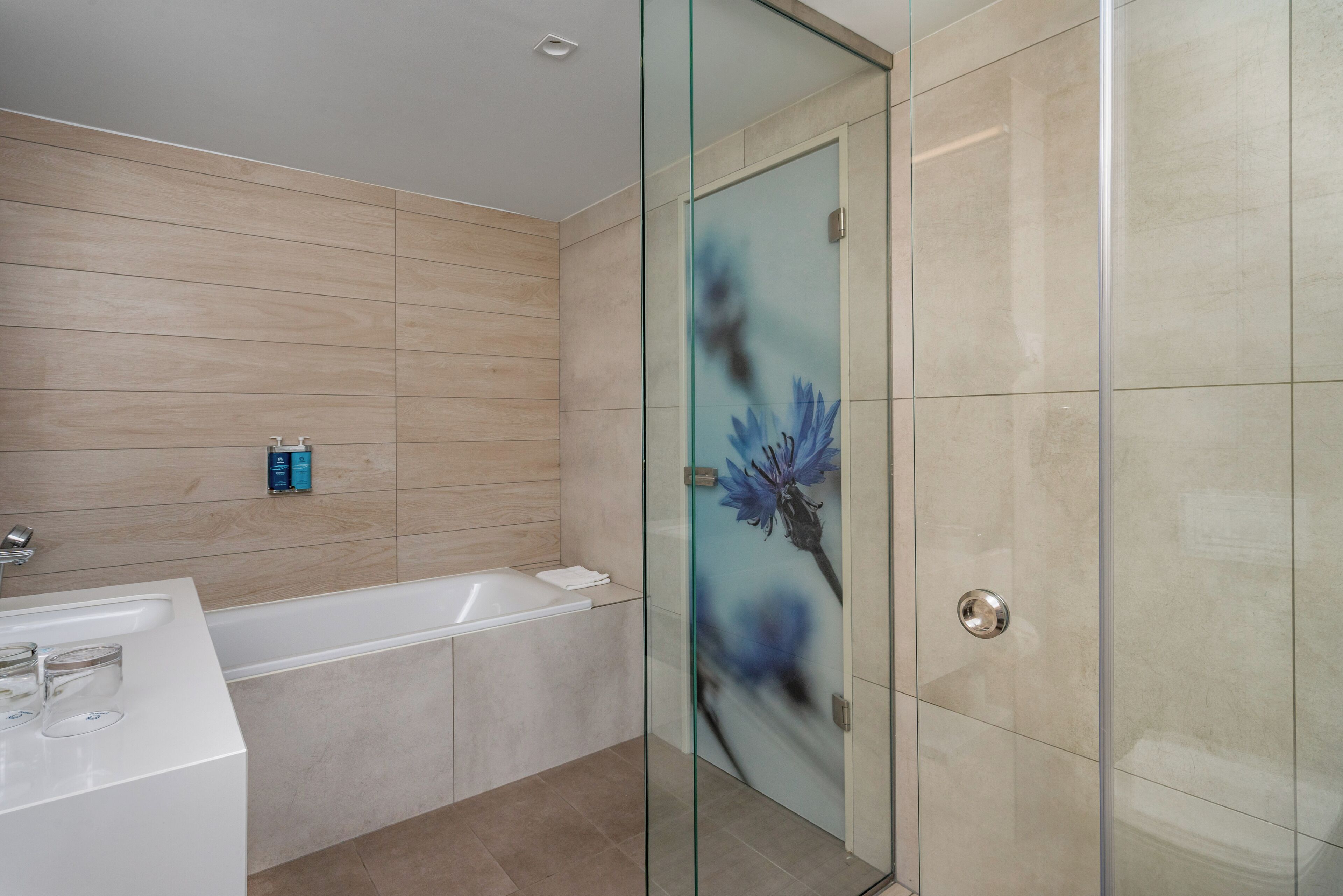 Un baño moderno con cabina de ducha de vidrio, bañera y tocador con lavabo.