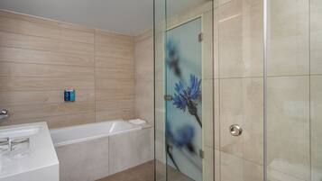 Un baño moderno con cabina de ducha de vidrio, bañera y tocador con lavabo.