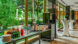 A modern hotel lobby with a glass table displaying various beverages and a buffet setup. - Ensana Thermal Margaret Island (Budapest)