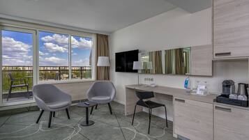 Habitació d'hotel moderna amb escriptori, dues cadires, televisió i una finestra gran que dona a una vista de la ciutat.