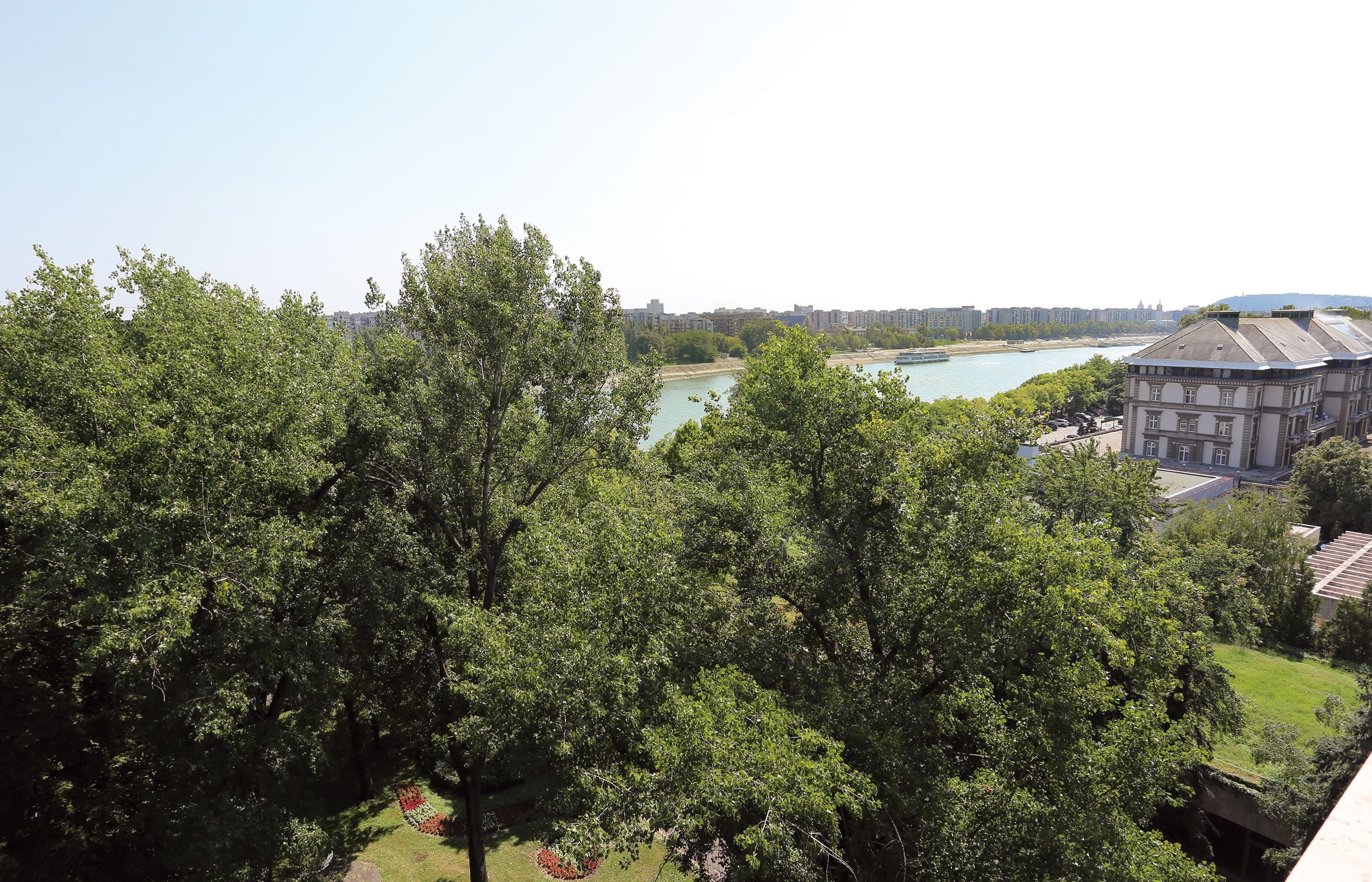 Une vue sur une rivière, avec des bâtiments et des arbres au premier plan.