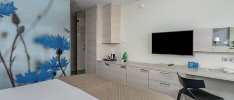 Una habitación de hotel moderna con cama, escritorio, silla, televisor de pantalla plana y un amplio ventanal.