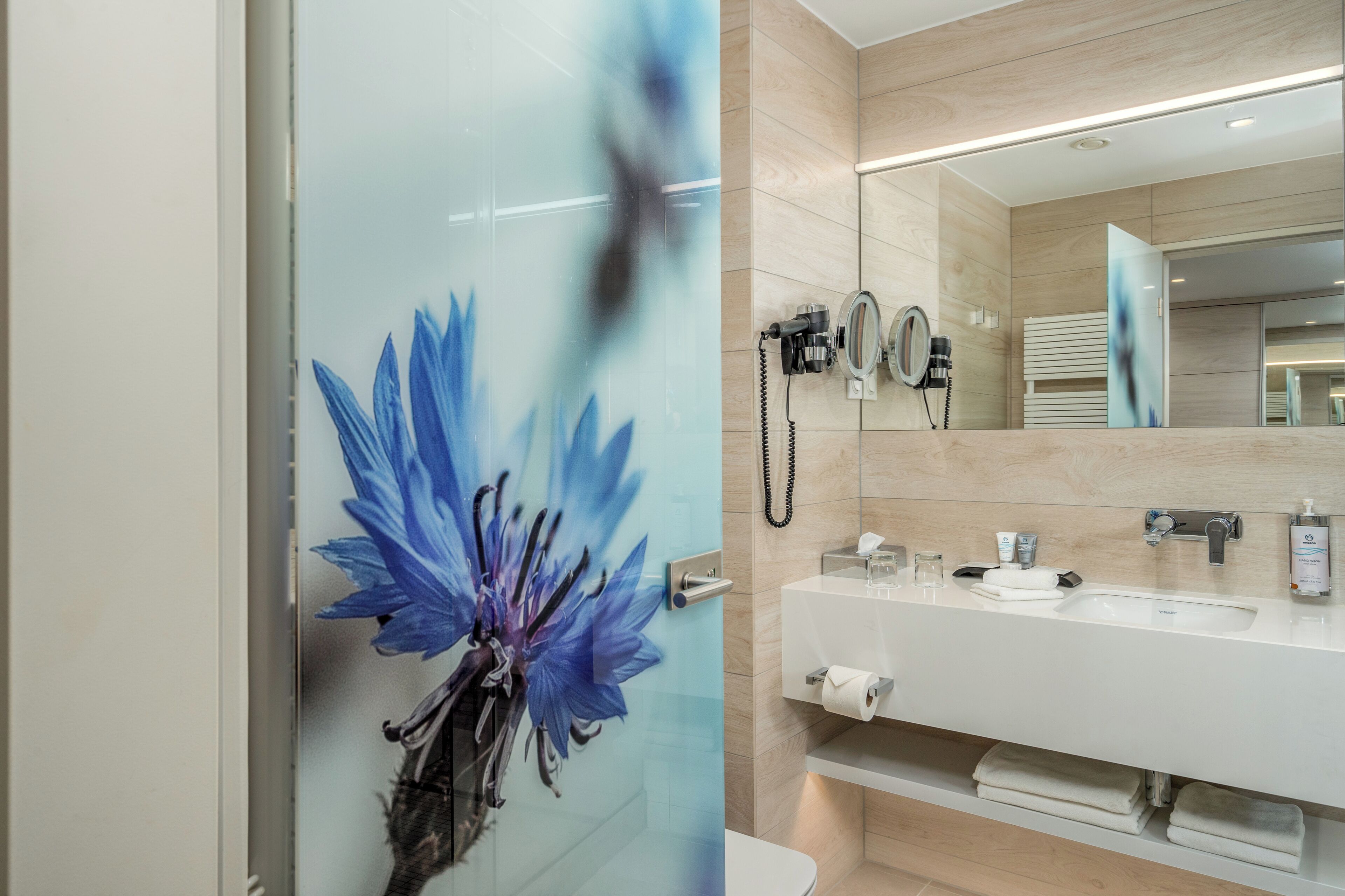 Un baño moderno con un espejo grande, un lavabo y un teléfono.