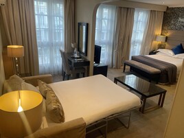 Ein Hotelzimmer mit einem Bett, einem Schreibtisch, einem Sessel, einem kleinen Tisch und einer Lampe.