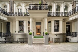 A grand entrance with a central staircase, flanked by two columns, leading to a balcony with ornate iron railings.
