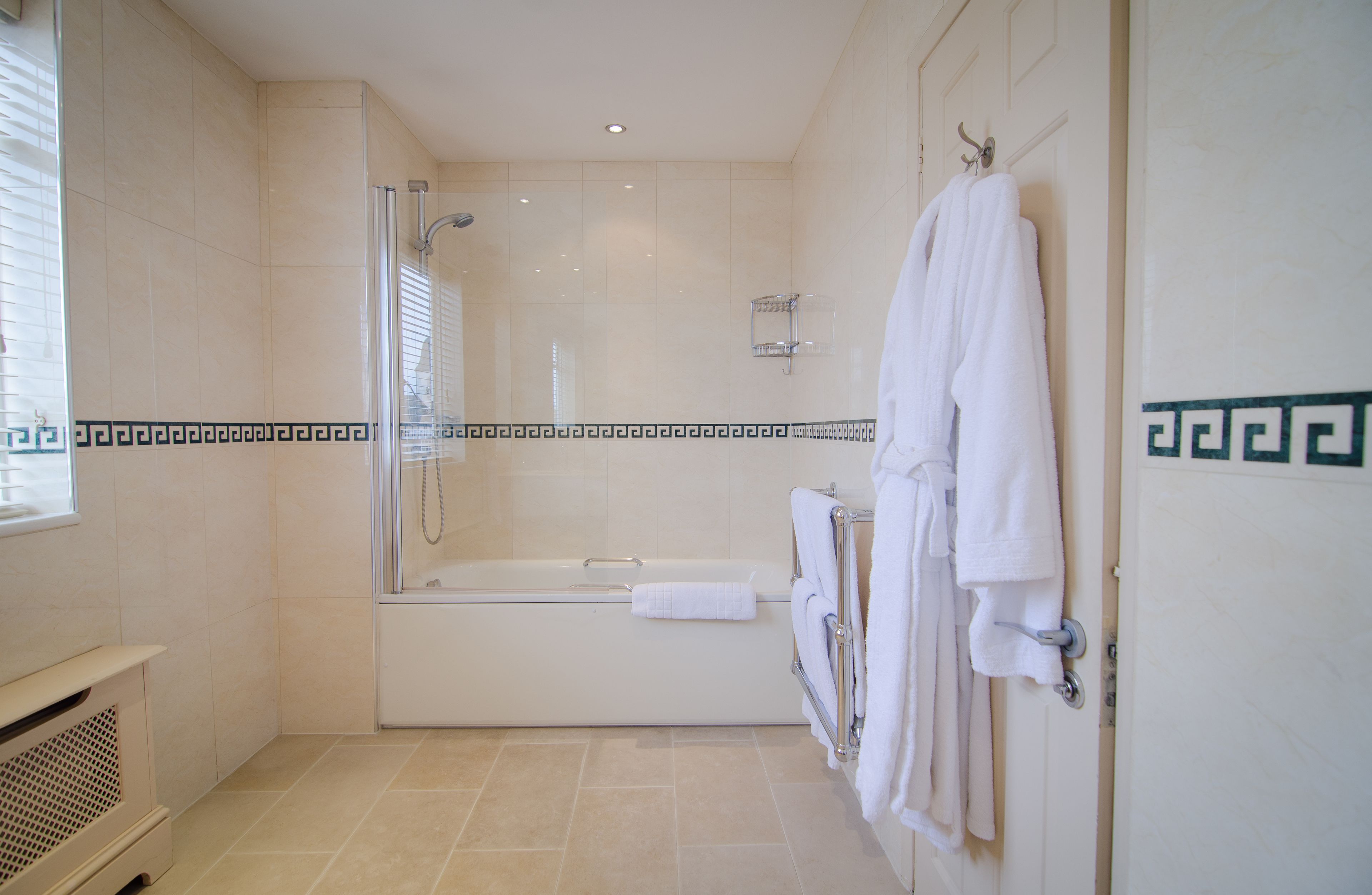A modern bathroom with a glass-enclosed shower, a bathtub, and a towel rack.