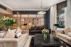 A modern living room with beige sofas, a black coffee table, and a large window with a view of buildings. - The Beaufort Knightsbridge (London)