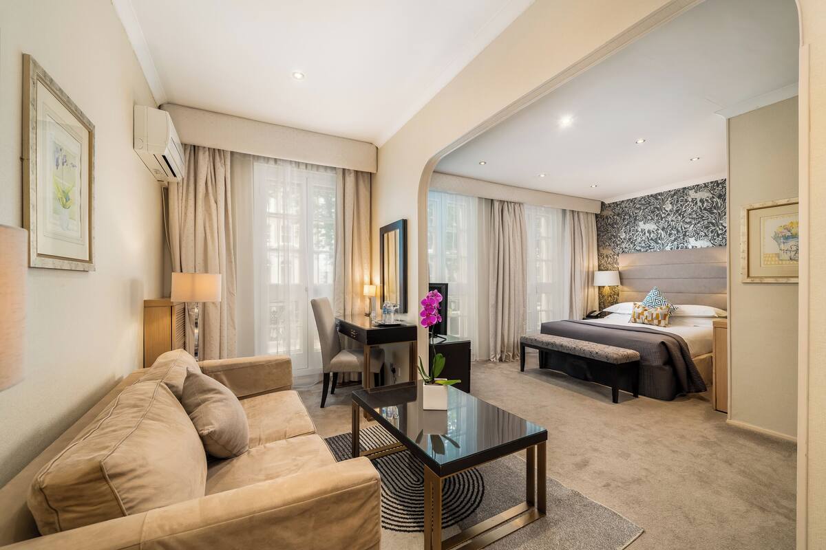 A hotel room with a sofa, a desk, a bed, and a coffee table.