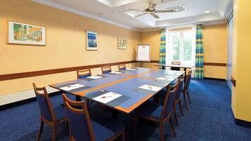 A conference room with a long table, chairs, a whiteboard, and framed pictures on the walls.
