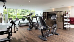 A modern gym with cardio machines, a weight bench, and a TV screen. - Leonardo Hotel Monchengladbach (Moenchengladbach)