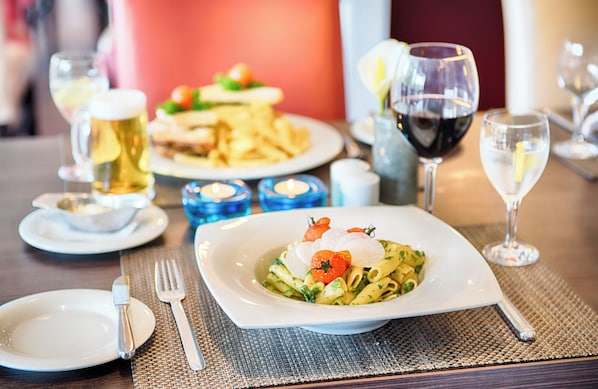 Una mesa de comedor con platos de comida, copas de vino y un candelabro como centro de mesa.