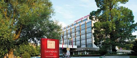 Un moderno edificio de hotel con un llamativo letrero rojo que dice Leonardo Hotel.