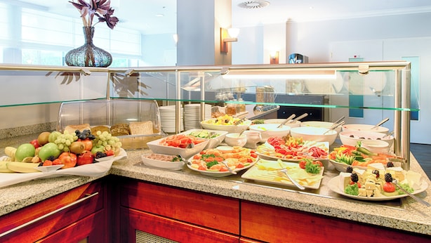 A buffet with various food items and a decorative vase. - Leonardo Hotel Monchengladbach (Moenchengladbach)