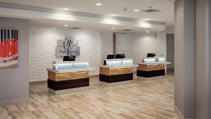 A hotel reception area with three reception desks, a wavy textured wall, and a ceiling with recessed lighting. - Holiday Inn Austin -Town Lake by IHG (Austin)