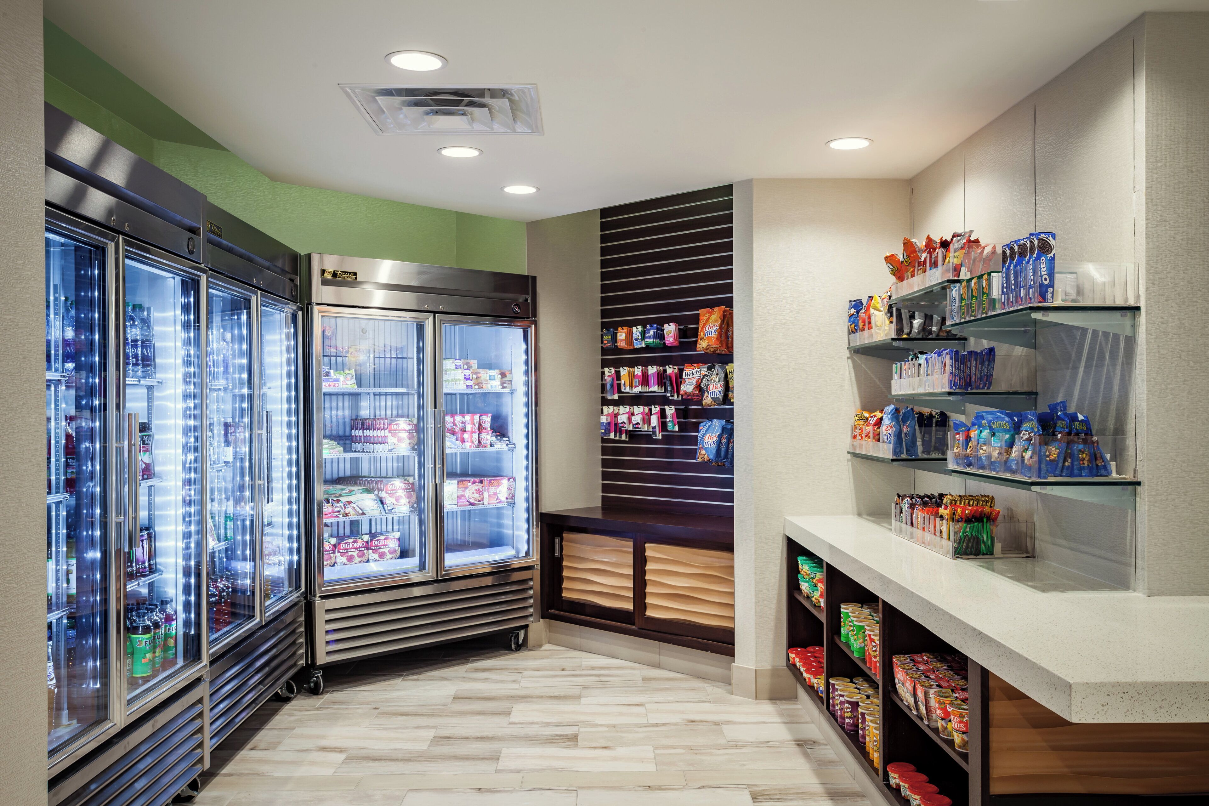 A grocery store interior with refrigerated sections, shelves stocked with snacks, and a checkout counter.