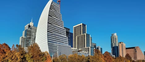 A modern city skyline with a prominent curved building and several other high-rise structures.