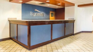 A reception desk with a blue and brown color scheme, a sign reading "Baymont," and a tiled floor.