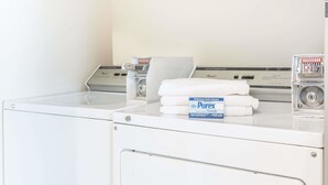 A laundry area with a washing machine, dryer, and a stack of white towels.