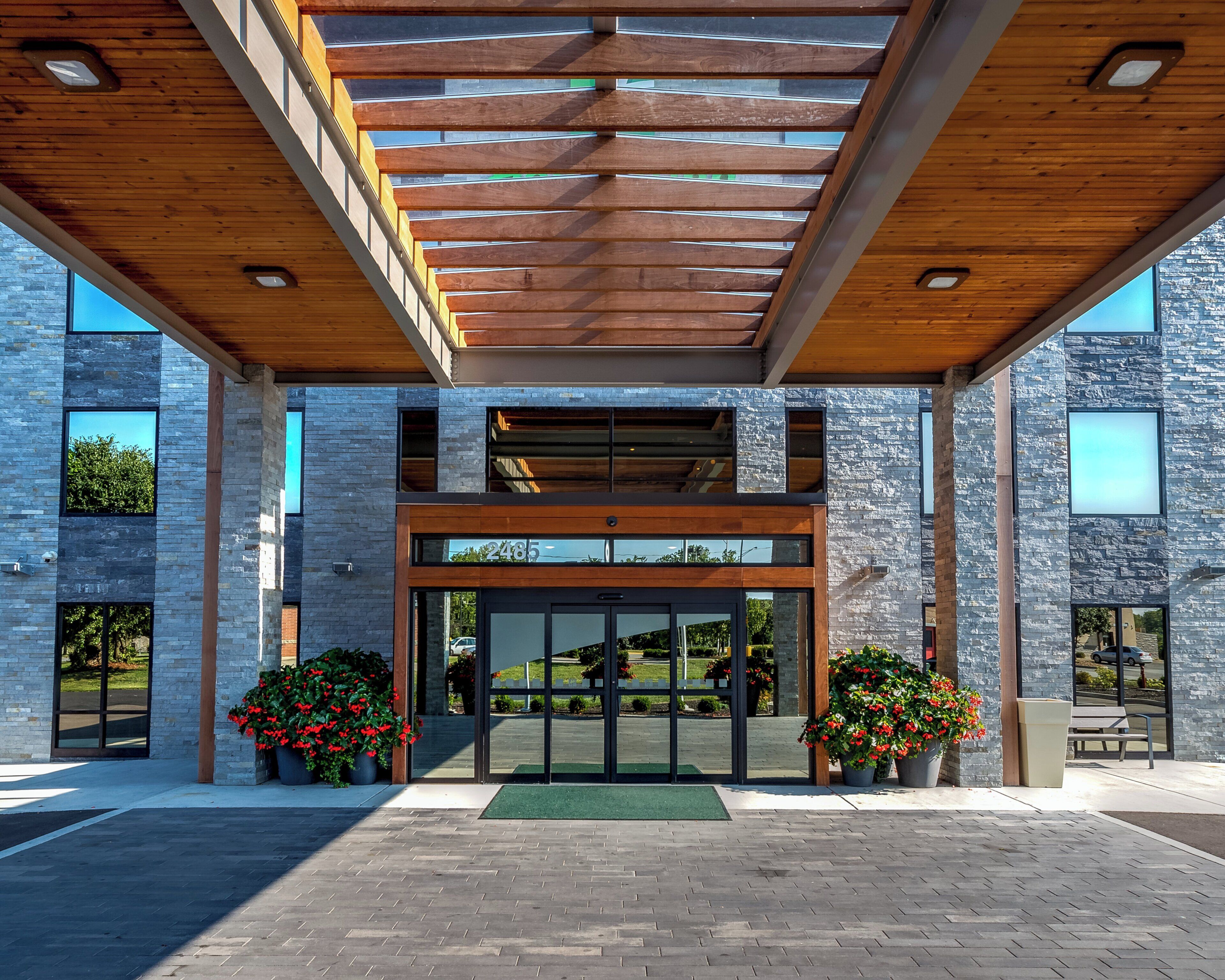 A modern building with a wooden ceiling, large glass doors, and stone walls.