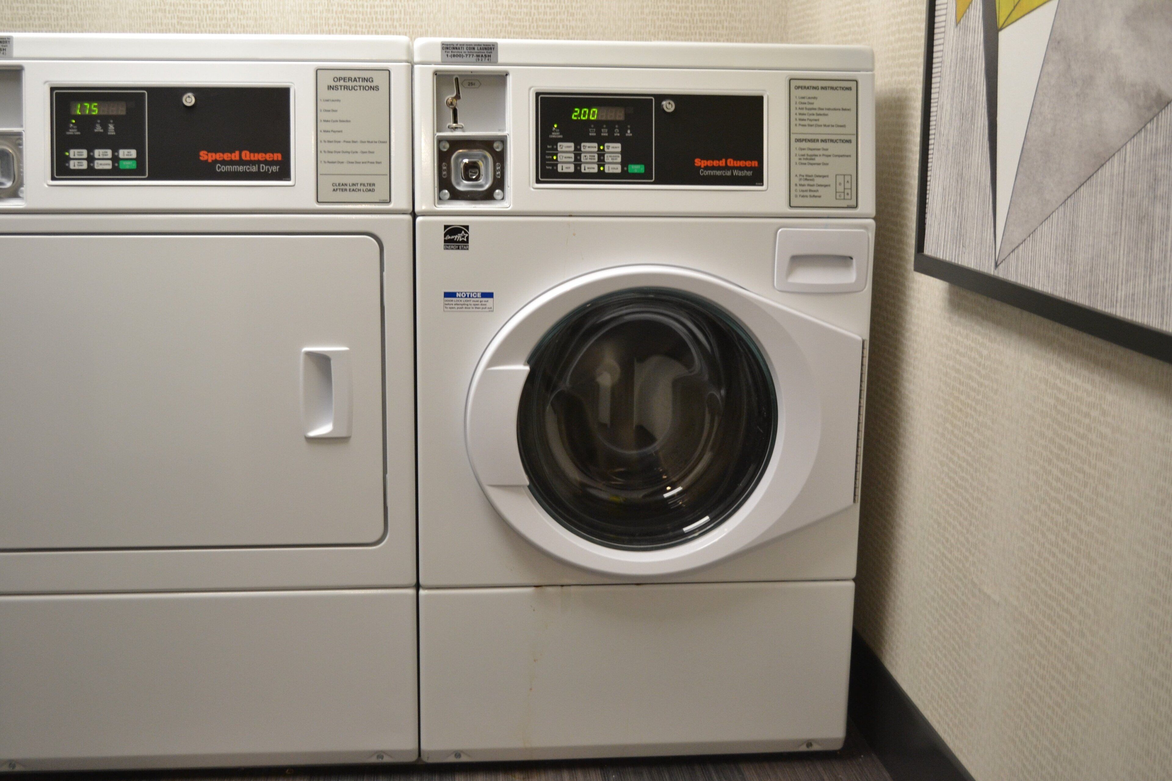 A front-loading commercial washer and dryer unit with digital displays and operating instructions.